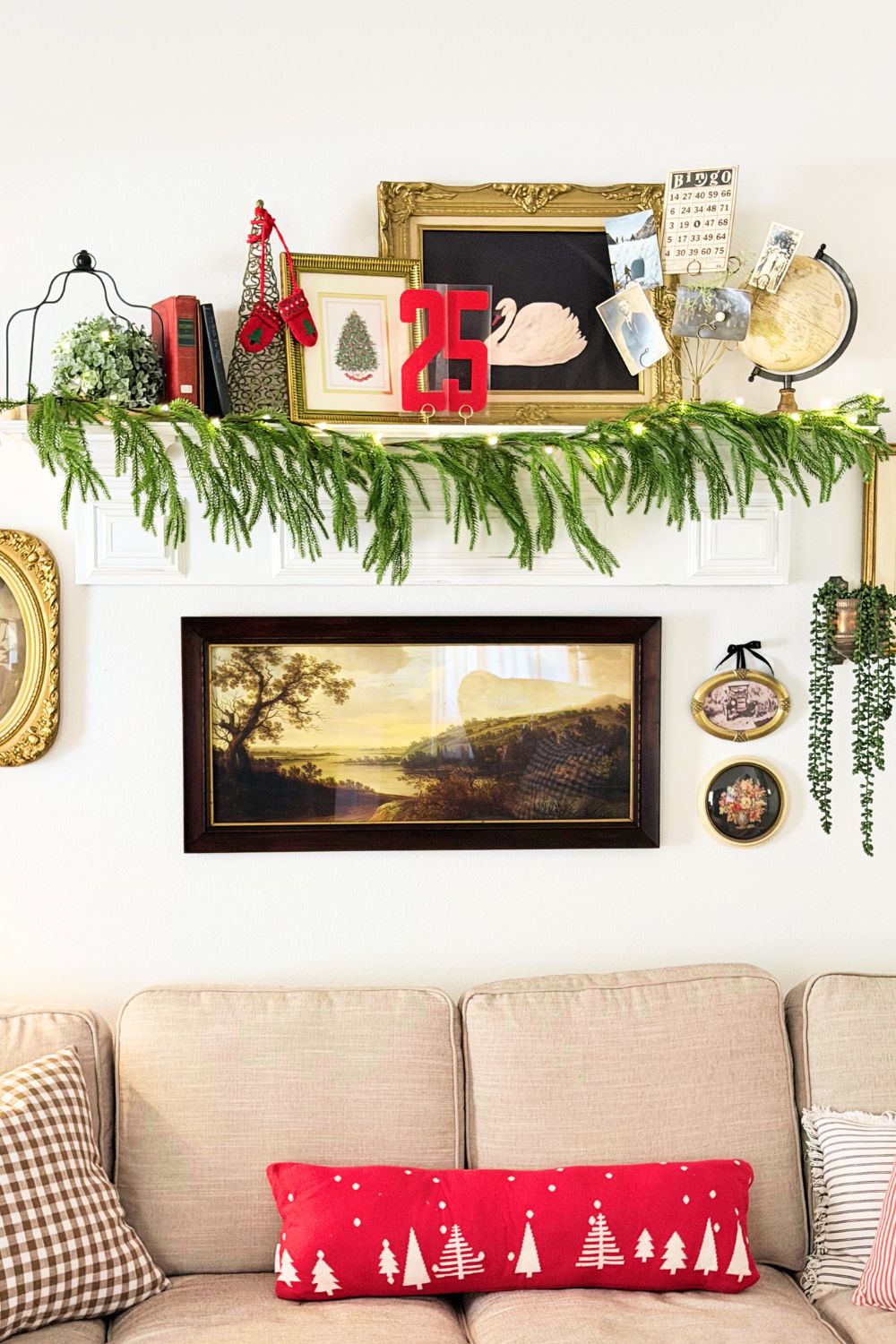 Layered farmhouse Christmas shelf decorated with vintage frames, greenery garland, marquee numbers, and collected holiday decor