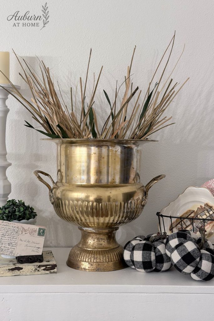 Brass bucket vase with dried stems.