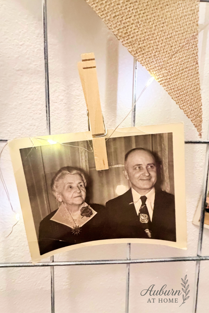 Close-up of vintage photos and burlap bunting clipped to a painted crib spring wall display
