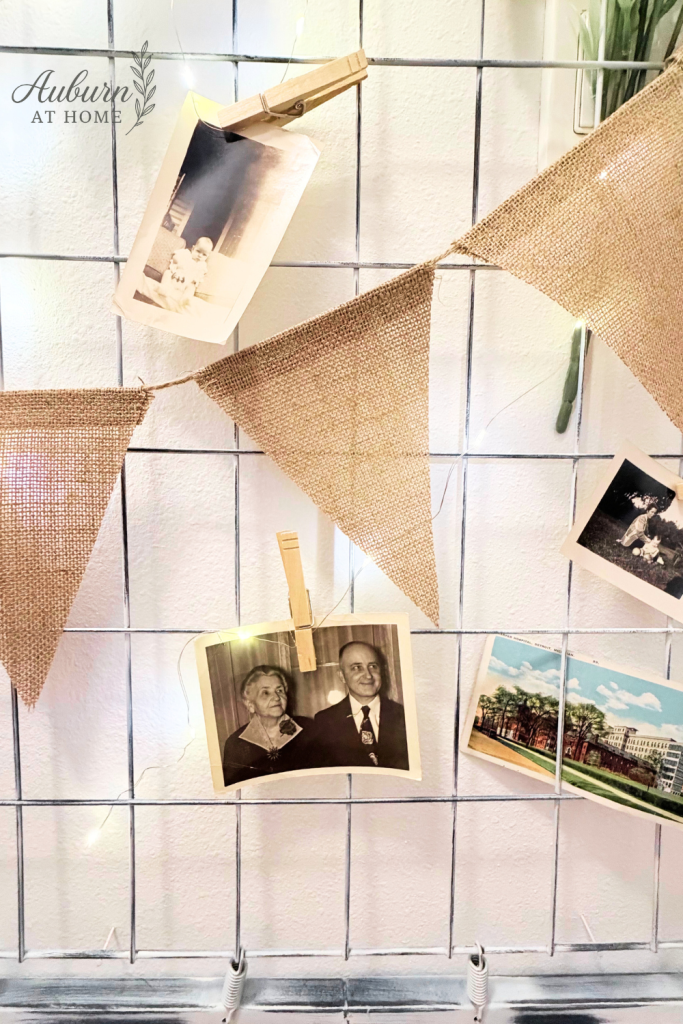 Close-up of vintage photos and burlap bunting clipped to a painted crib spring wall display