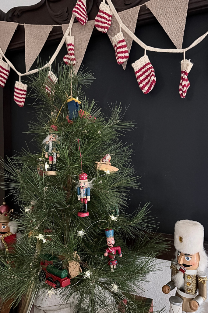 Close-up of a vintage Christmas vignette featuring a tabletop pine tree with nutcracker ornaments, a red Coca-Cola crate filled with nostalgic holiday decor, and warm, cozy Christmas accents.