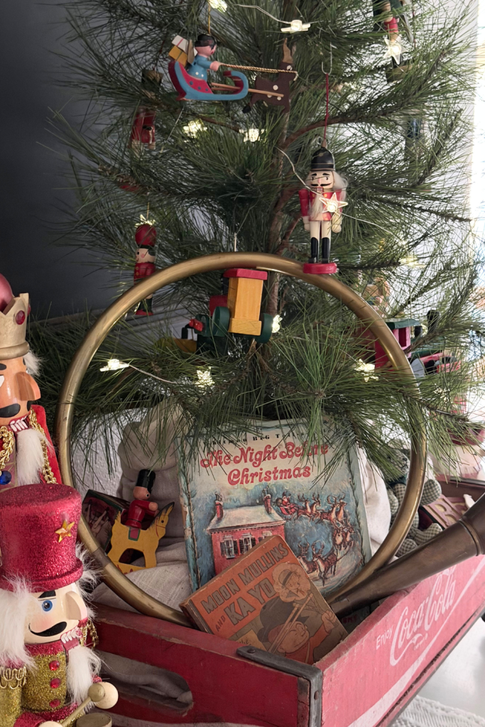 Close-up of nutcracker ornaments hanging on a small tabletop Christmas tree with pine branches, styled in a vintage holiday theme.