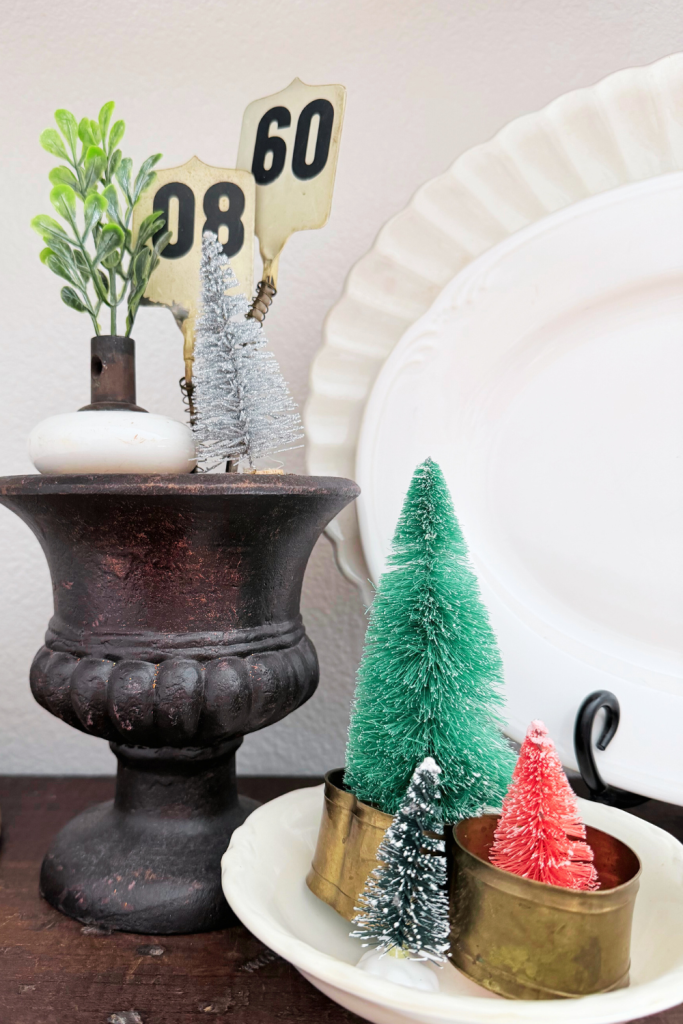 Bottlebrush Christmas trees displayed in small brass containers and styled beside a rustic pedestal bowl for a simple, colorful holiday vignette.