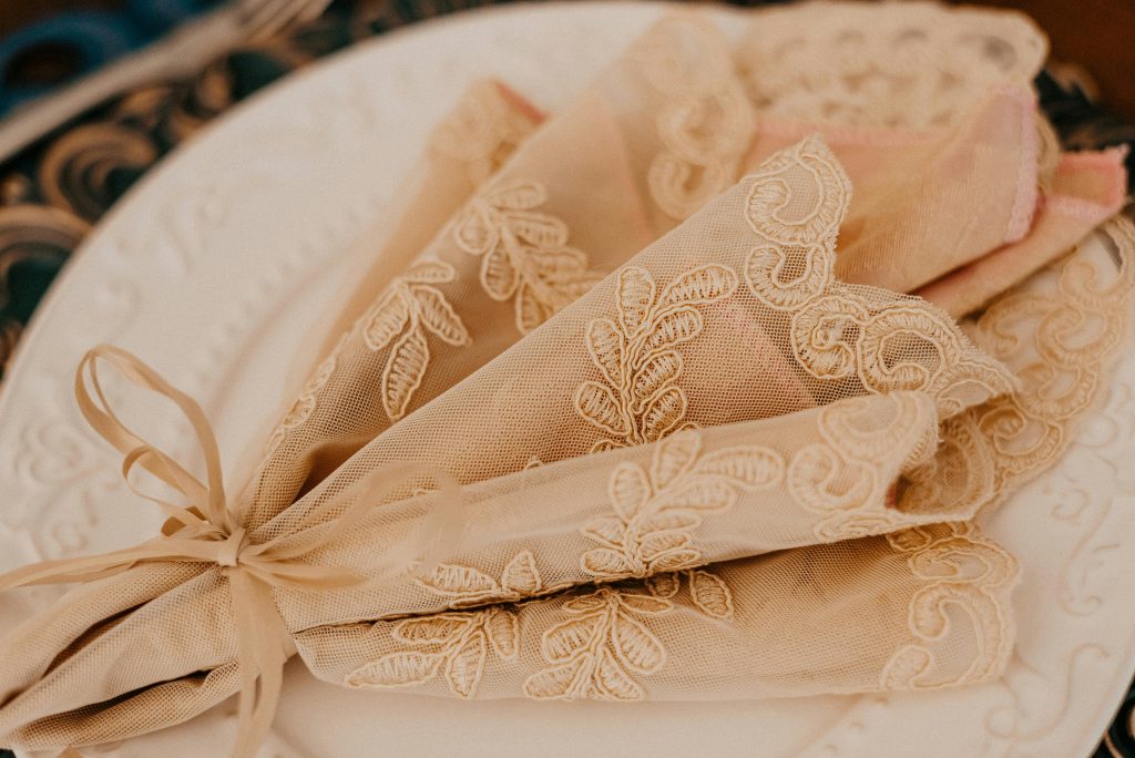 Vintage lace linens in soft ivory tones folded and layered for Valentine’s Day table decor